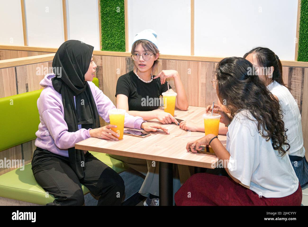 Young Asian women having a great time in a cafe. Drinking orange juice and socializing. Stock Photo