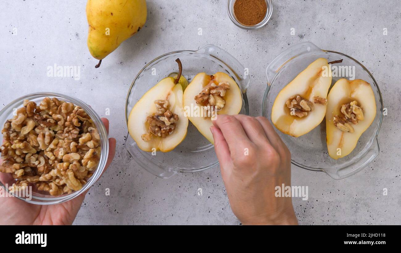 Baked pears with walnuts, honey, and cinnamon, close up on rustic background, perfect breakfast or dessert, flat lay, woman hands Stock Photo