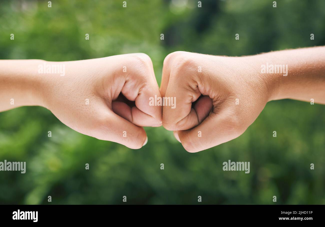 Closeup of a fist bump outside in nature. Two diverse peoples hands greeting. Fist bump in nature. Closeup of a fist bump outside in nature. Two Stock Photo