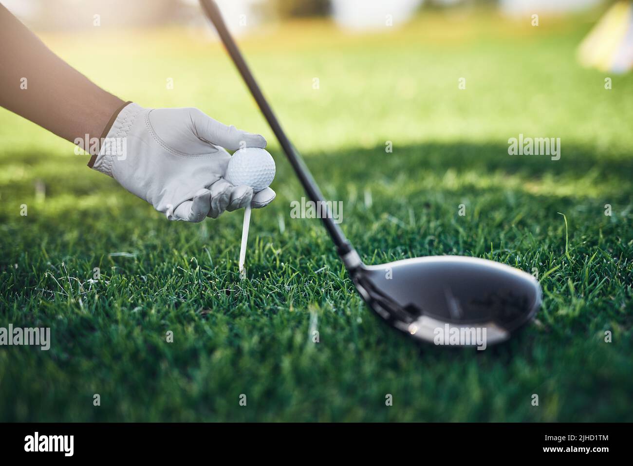 Im sorry but Im going to hit you far away. Closeup shot of an unrecognizable person putting a golf ball on top of a golf peg with a golf club standing Stock Photo