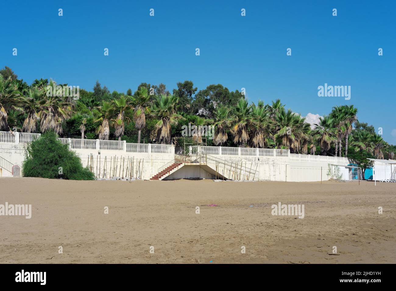 Wall at sandy beach with palm trees over it Stock Photo