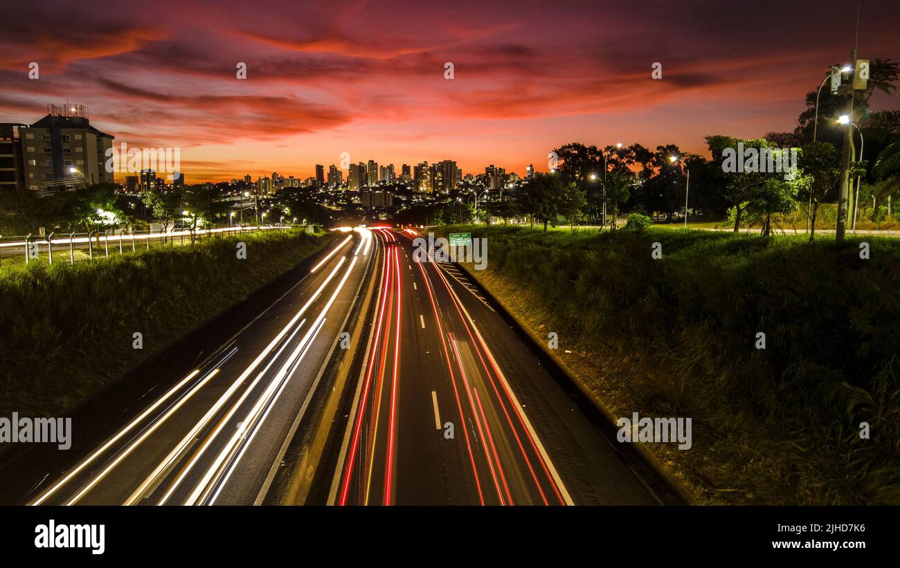Trail of light caused by vehicular traffic in SP-294, Comandante Joao Ribeiro Barros Highway with buildings from downtown in the background, in Maríli Stock Photo