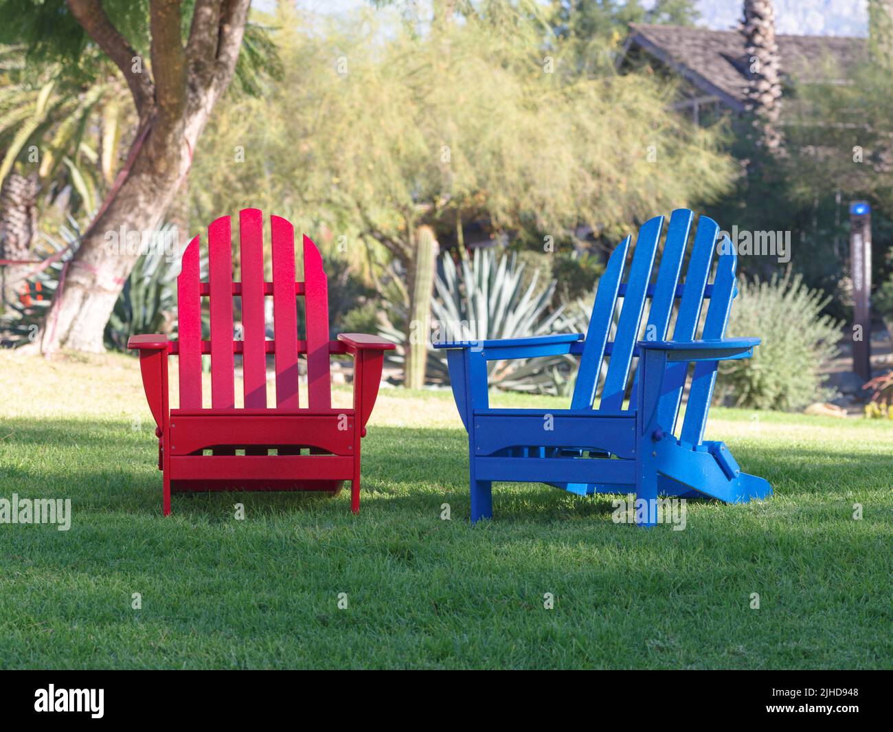 Red and Blue Adirondack Chairs on Lawn - Morning Stock Photo
