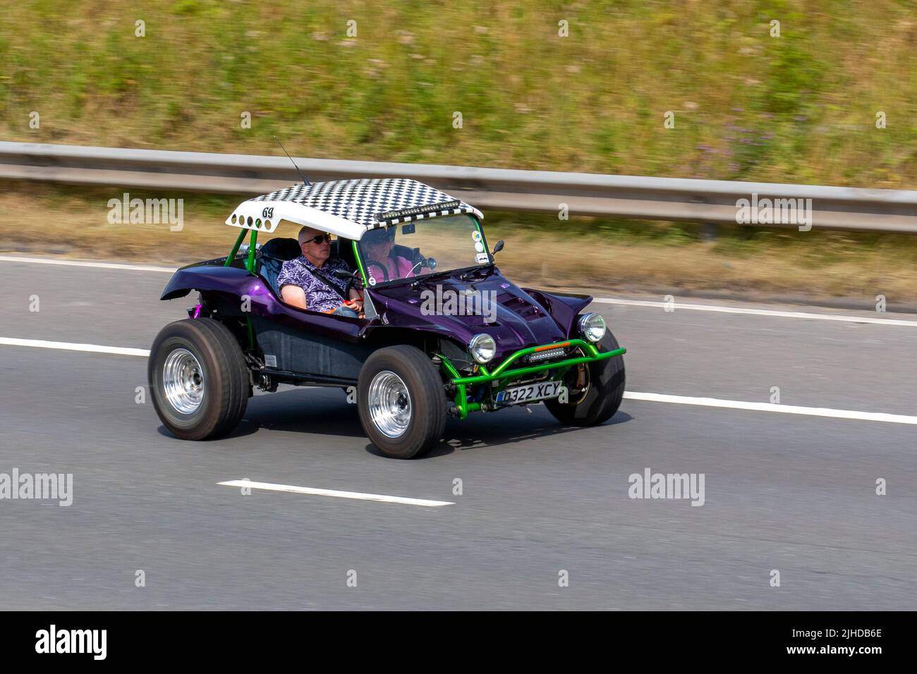 Purple VW Volkswagen Beach Buggy 1980cc petrol, Dune buggy minimalist machines with Metalflake purple, big chrome roll-over bar, huge tyres; travelling on the M6 motorway UK Stock Photo