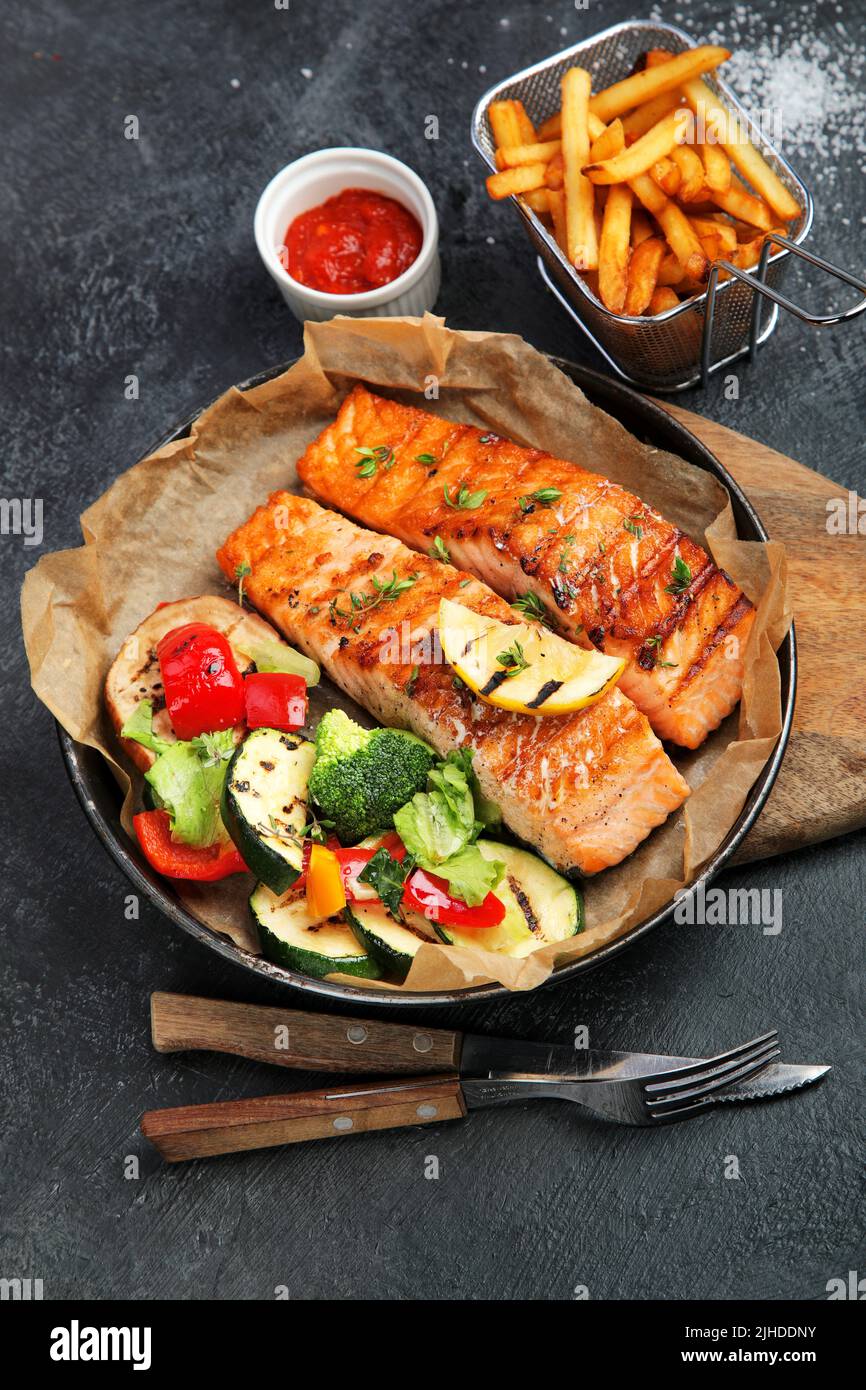 Salmon steak with vegetables on dark background. Freshly grilled ...
