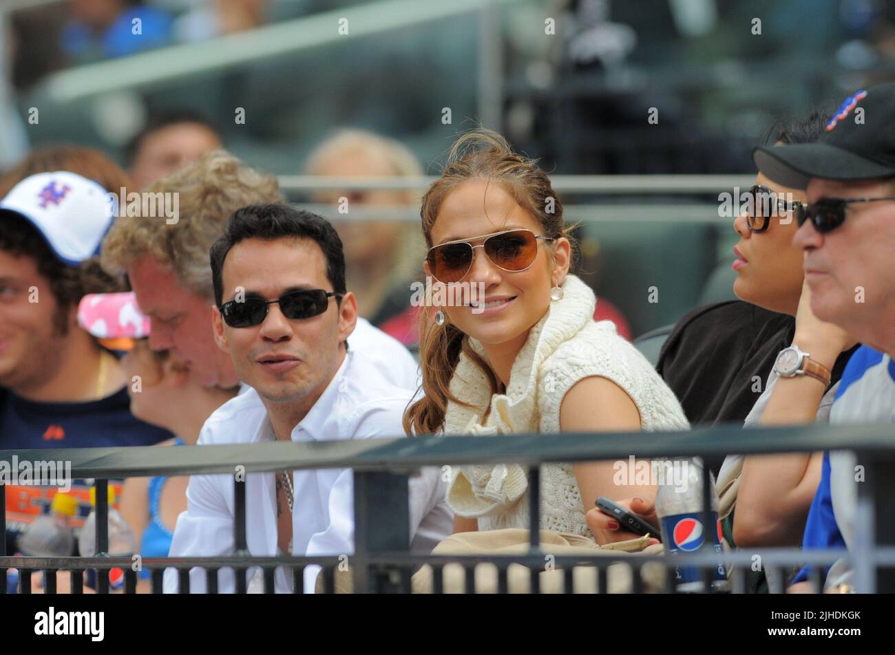 NEW YORK - JUNE 21;  Actress Jennifer Lopez and husband Marc Anthony watch the game between the Tampa Bay Rays and the New York Mets at CitiField. J-Lo looked a little tired and she frequently was caught yawning, and resting on Marcs shoulder. meanwhile Marc Anthony spent time picking his teeth. Jennifer was also seen picking off lint or dirt from marcs collar. The two than enjoyed some peanuts and candy as they watched the game with friend Carlos Beltran wife Jessica (black hair to the left of Jennifer)    on June 21, 2009 in Queens, New York  People:  Jennifer Lopez, Marc Anthony Stock Photo