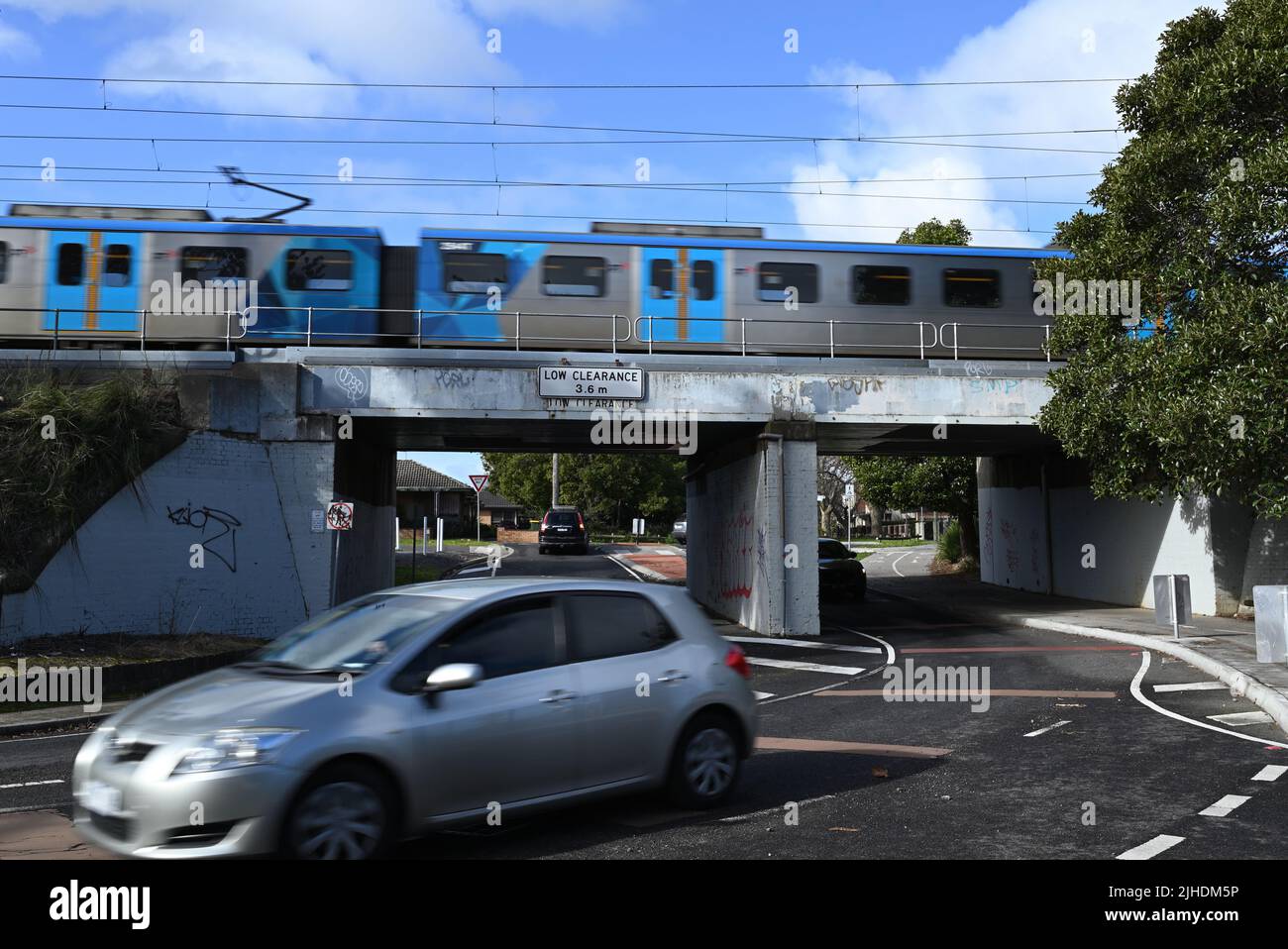 Woodville Ave rail bridge, with train traveling across it while cars go underneath it Stock Photo