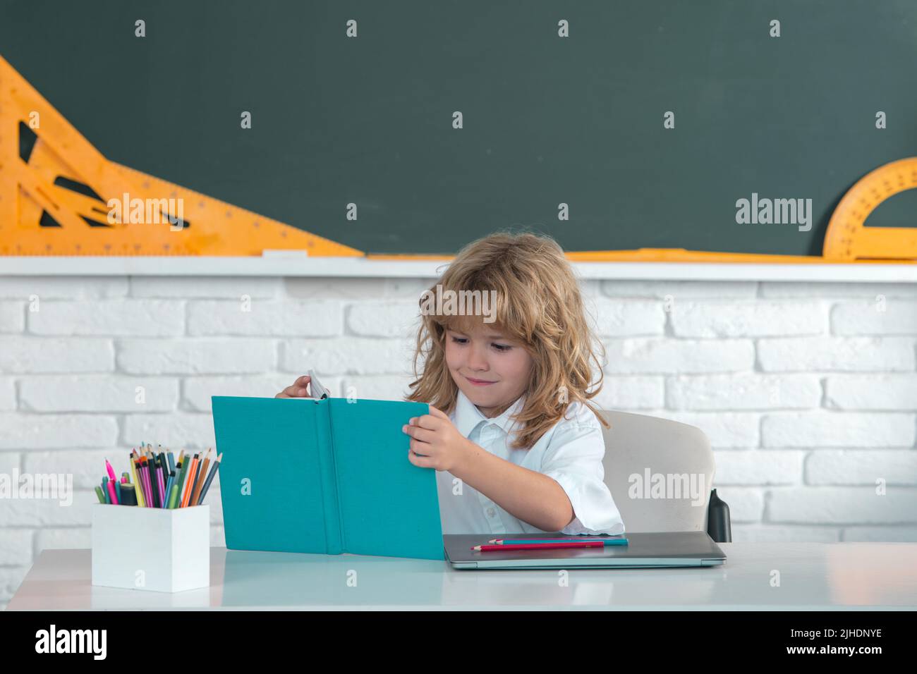 Cute little school kid boy read book in a classroom Stock Photo - Alamy