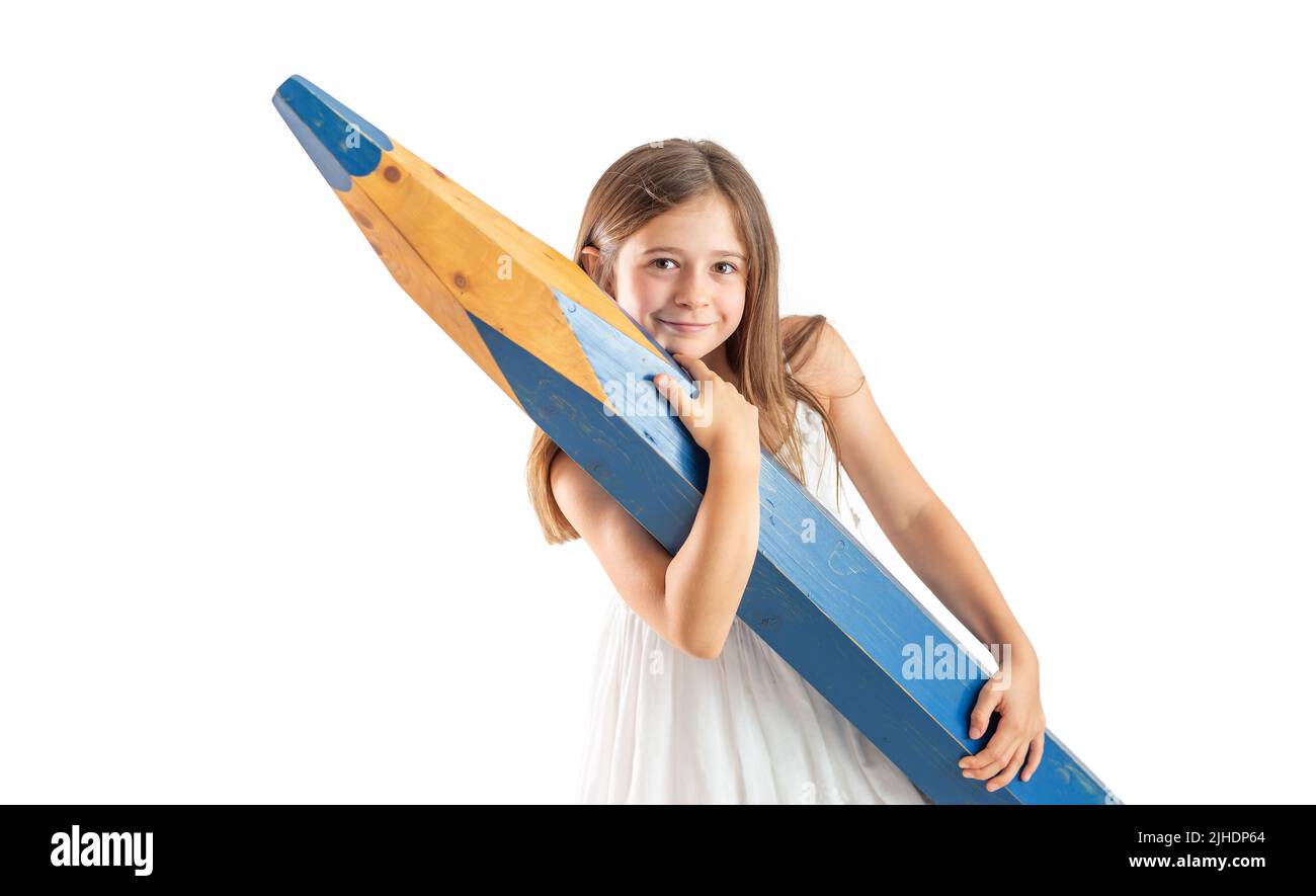 A cute little girl with great effort holds a huge blue pencil in her hands - isolated on white. Stock Photo