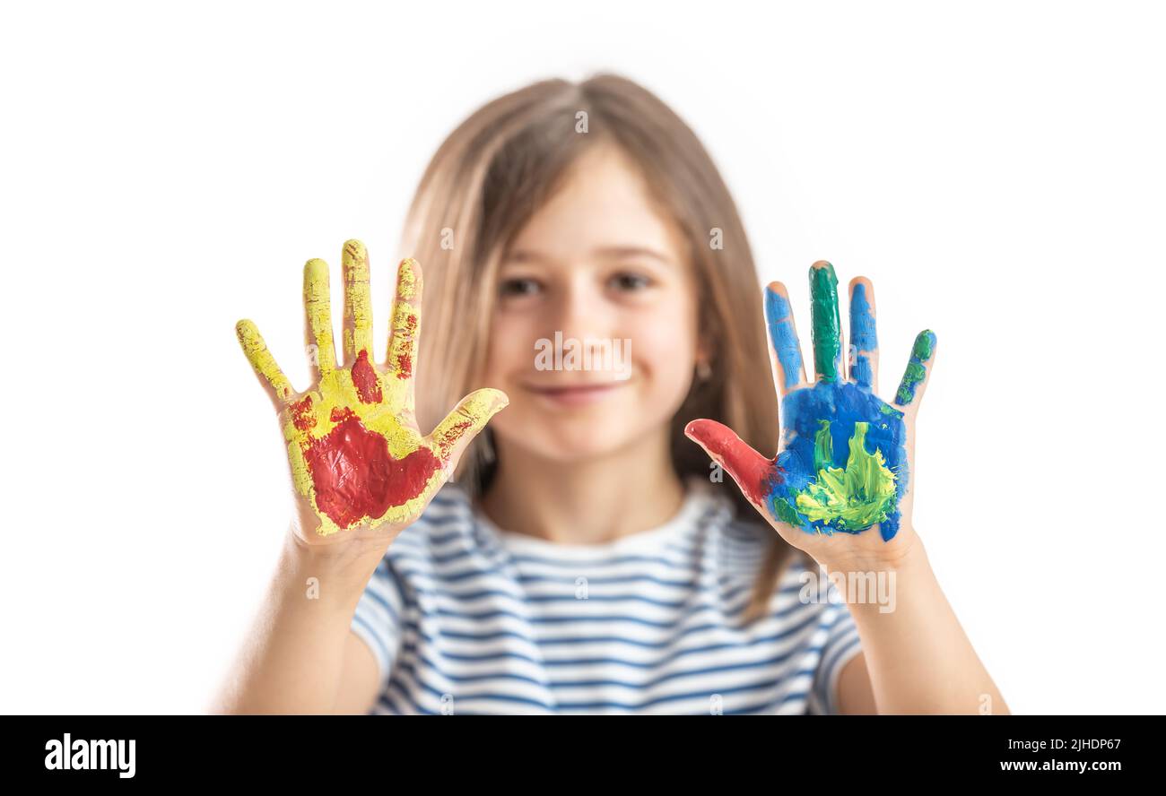 Little schoolgirl shows hands painted with watercolors - isolated on white. Stock Photo