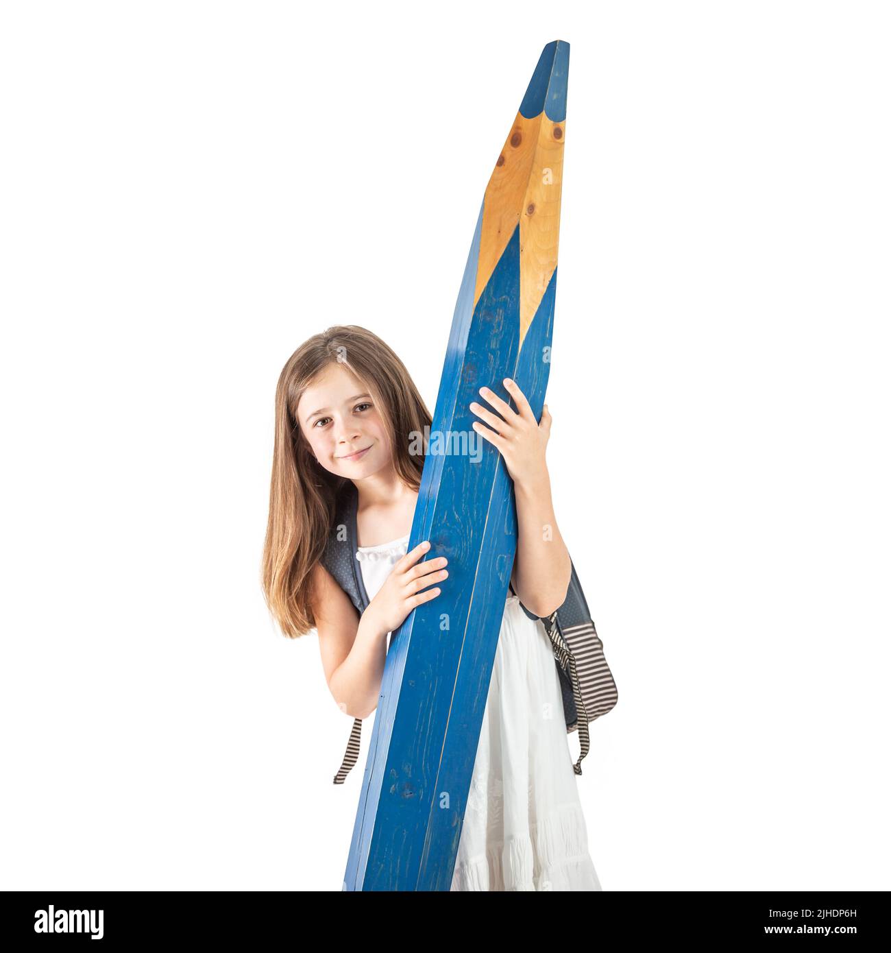 Cute little girl with a school bag holds a huge blue pencil in her hands - Isolated on white. Stock Photo