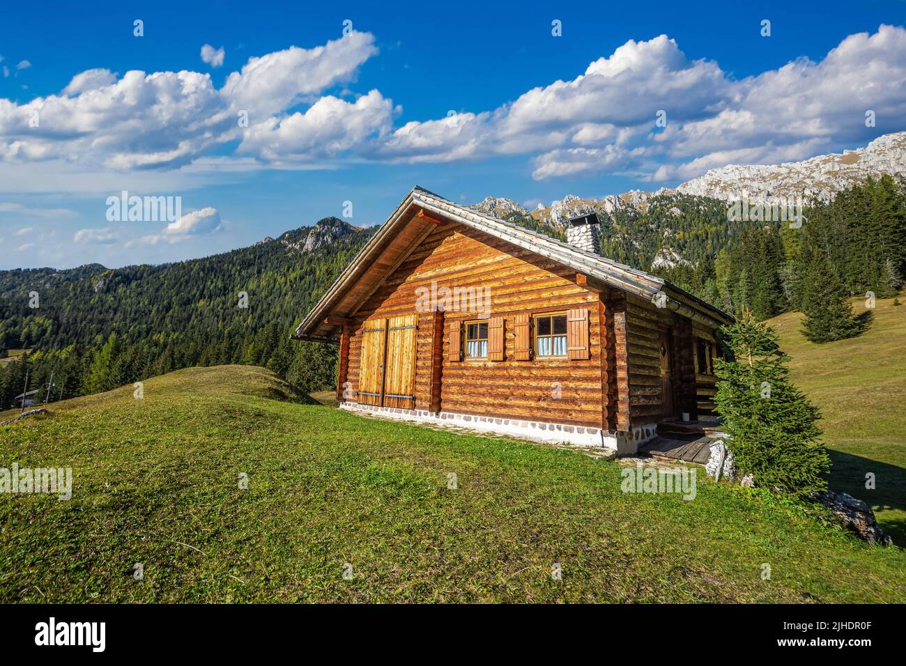 Dolomites, Italy - Traditional wooden chalet in the Italian Dolomites on a sunny summer day with blue sky and clouds Stock Photo