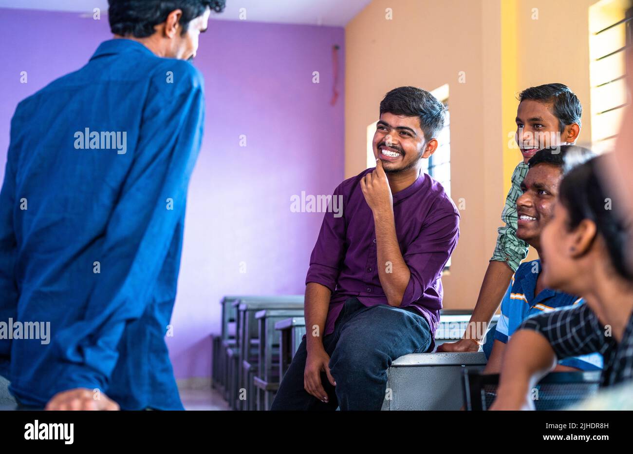 group od Happy smiling college students having chat with each other at classroom during leisure - concept of taking break, friendship and knowledge Stock Photo