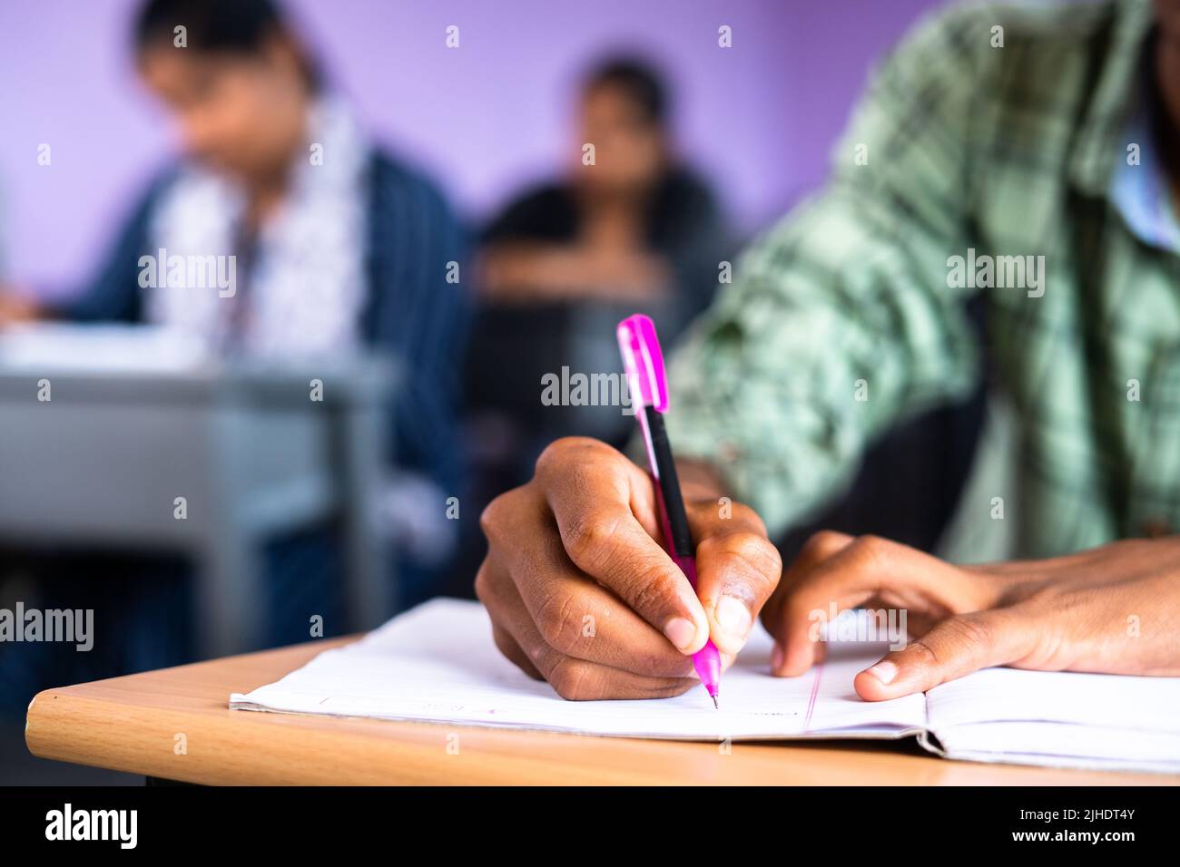 Close up shot of college student writing notes on book at classroom - concept of examination, development and education Stock Photo