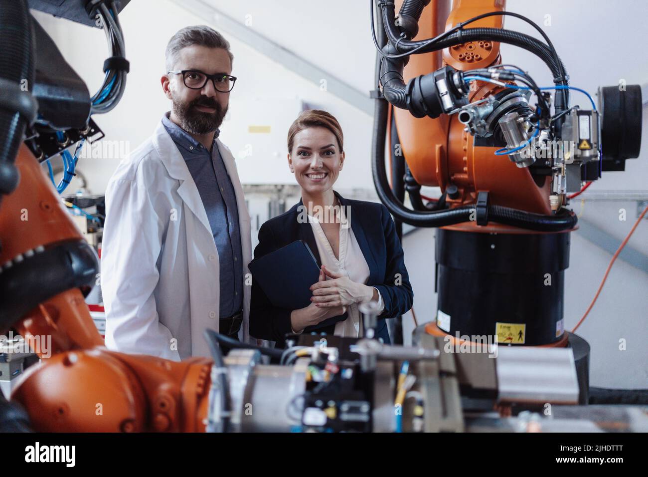 Robotics engineers with tablet dicussing and desinging modern robotic ...