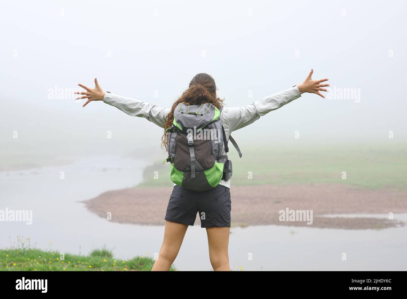 Back view portrait of a hiker outstretching arms in the mountain a foggy day Stock Photo