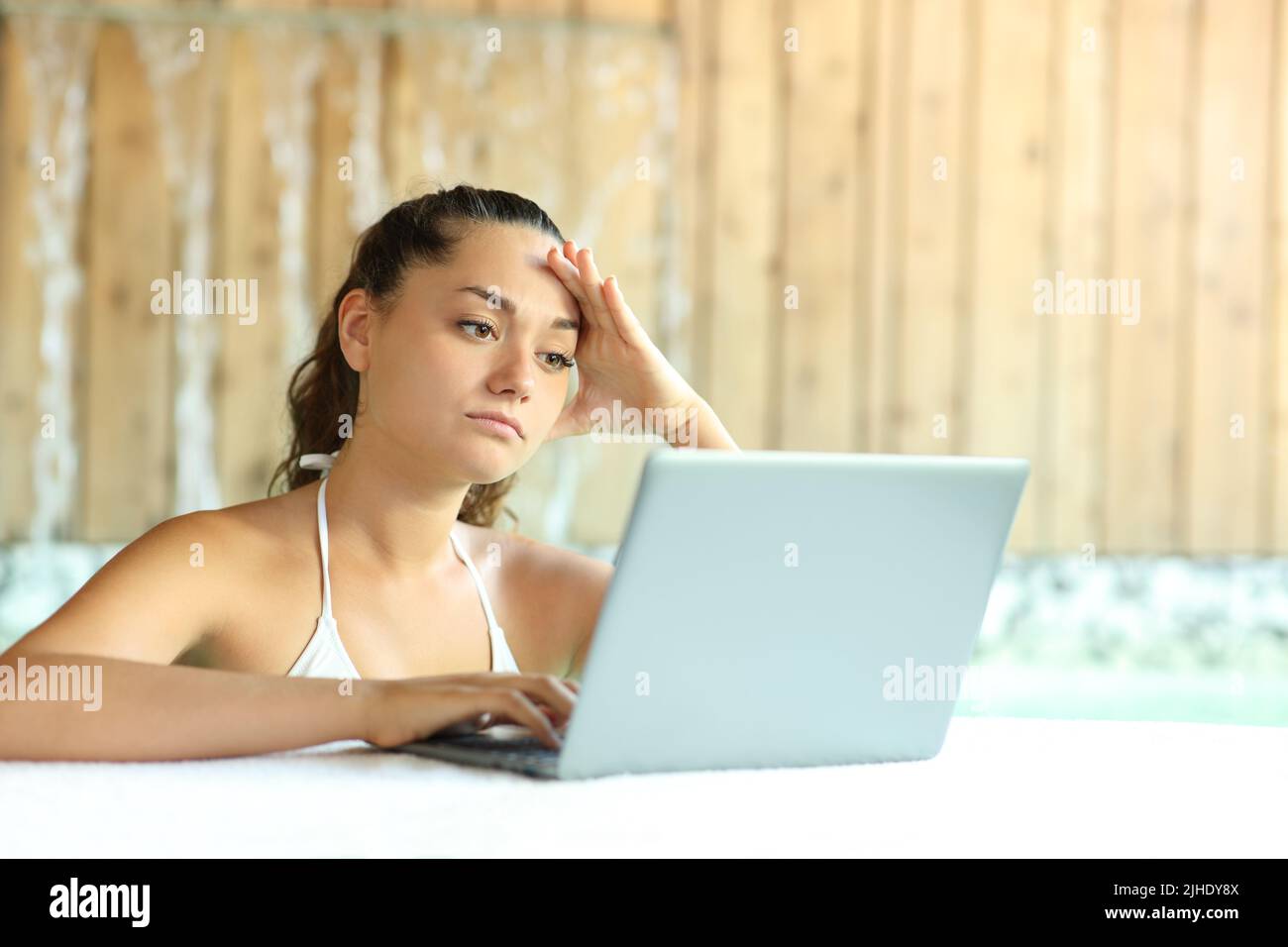 Worried woman unable to relax using laptop in spa Stock Photo