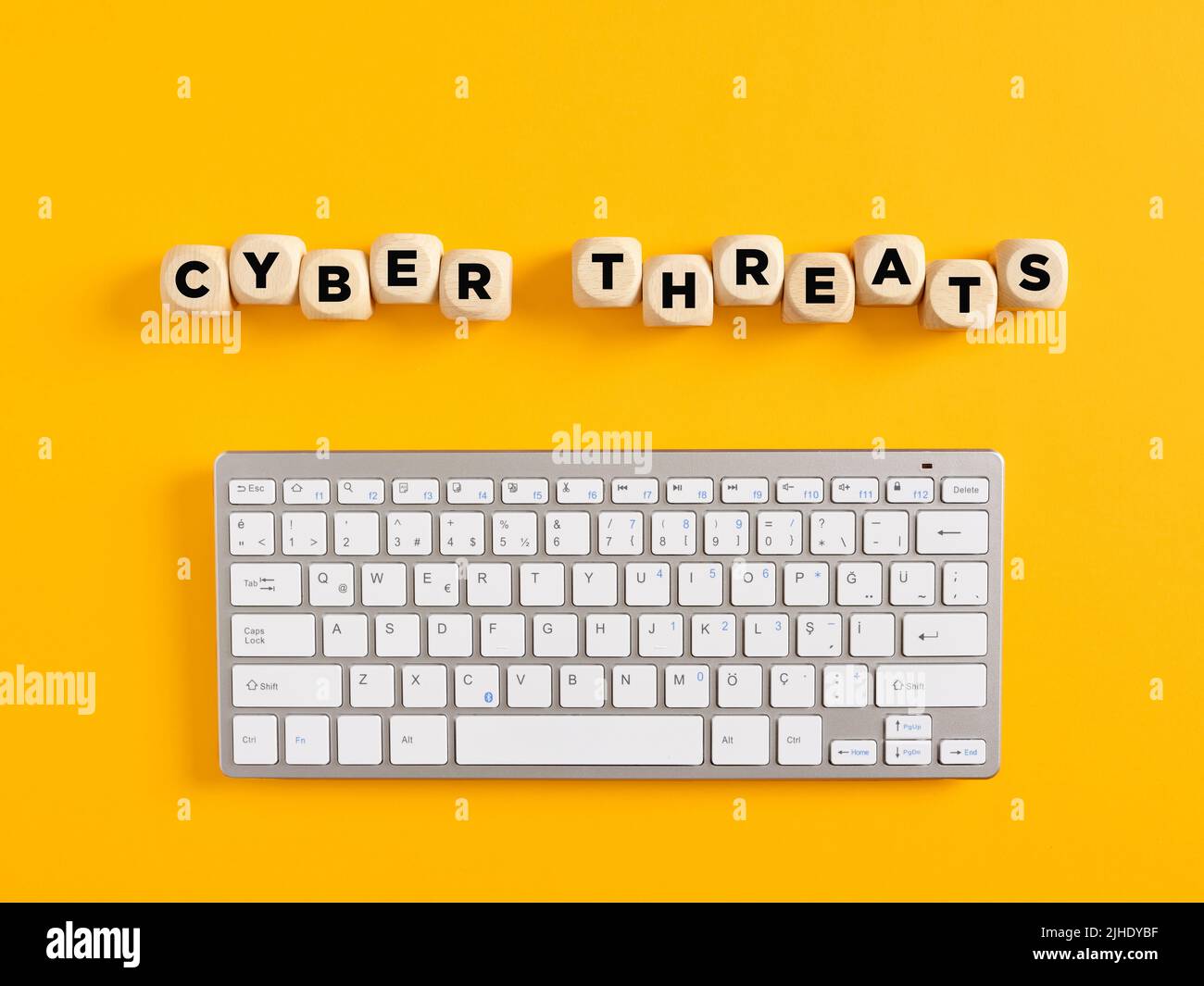 The word cyber threats with computer keyboard on yellow background. Cyber attack and security concept. Stock Photo