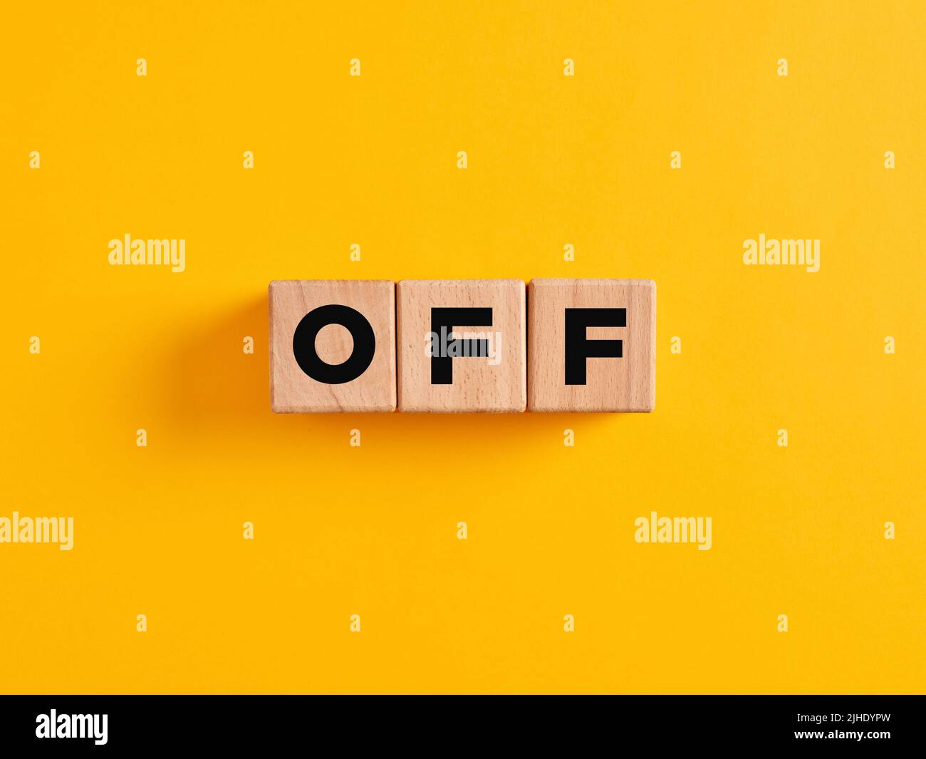 The word off on wooden cubes on yellow background. To end or to close concept. Stock Photo