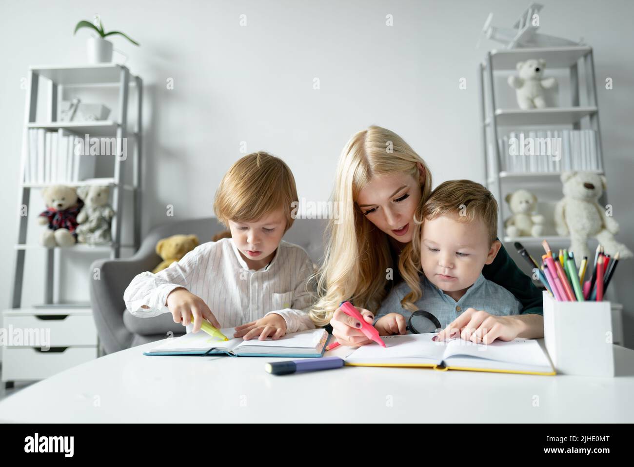 Teacher helping school child in class at school. Little children with ...