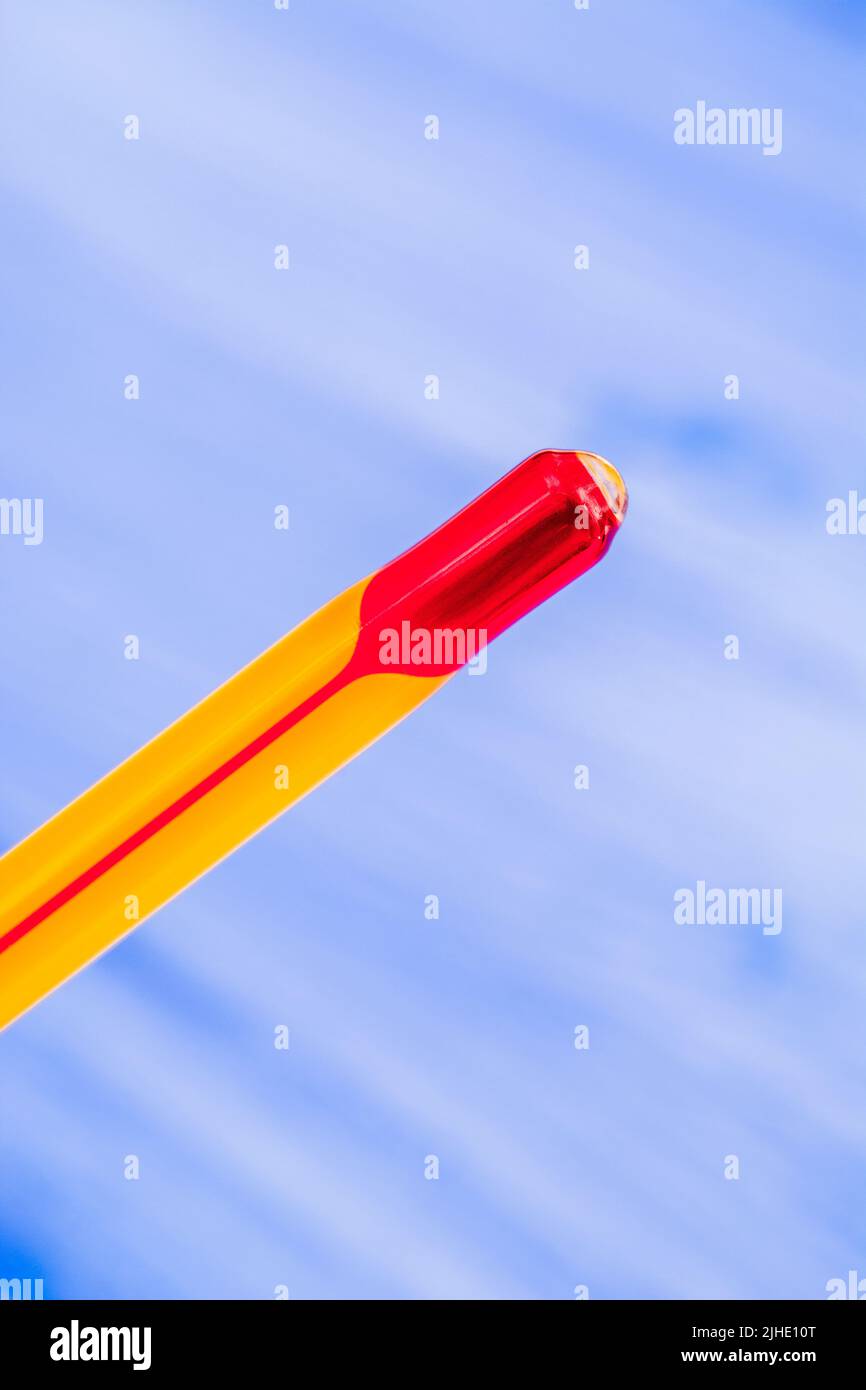 Glass red ink thermometer bulb on a colour background. For 2022 Summer heatwave, UK heatwave, hot weather, high temperatures, red hot, severe heat. Stock Photo