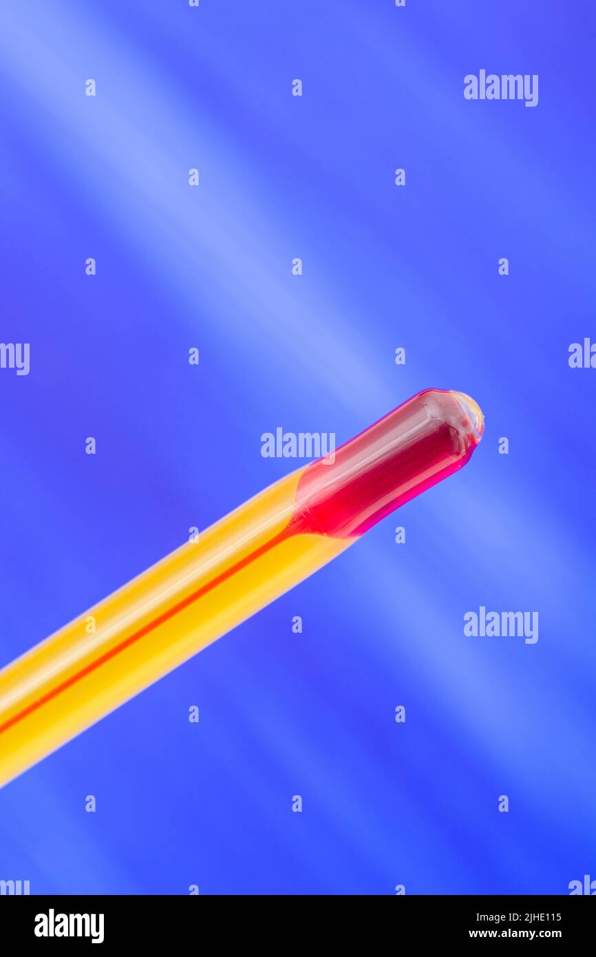 Glass red ink thermometer bulb on a colour background. For 2022 Summer heatwave, UK heatwave, hot weather, high temperatures, red hot, severe heat. Stock Photo