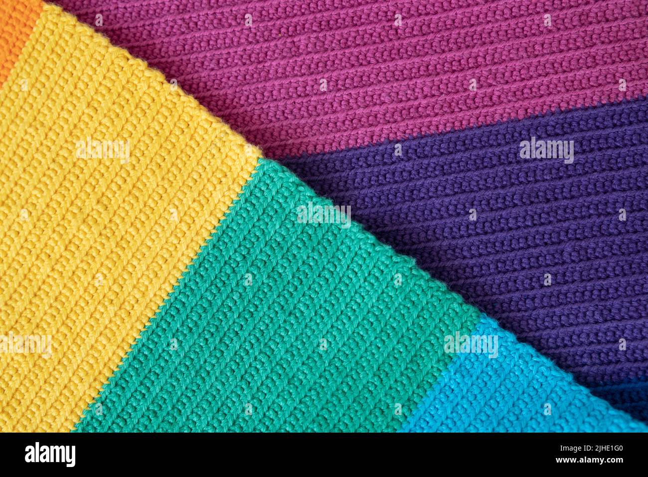 Close-up detail of a crocheted fabric created from various colors yarn using a single stitch technique, beautiful pattern made from interlocking loops Stock Photo