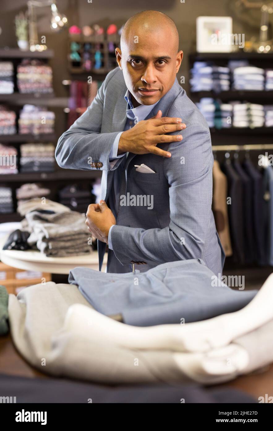 Man choosing suit jacket in clothing store Stock Photo - Alamy