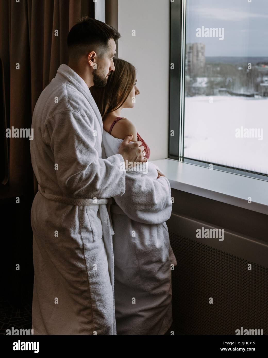 Couple wearing bathrobes in hotel standing near window Stock Photo Alamy
