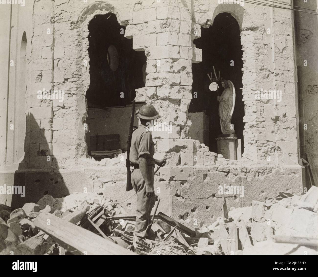 A vintage photo dated December 9th 1941 showing a British soldier looking at the bomb damaged ruins of a catholic church after the siege of Tobruk Libya North Africa during world war two Stock Photo