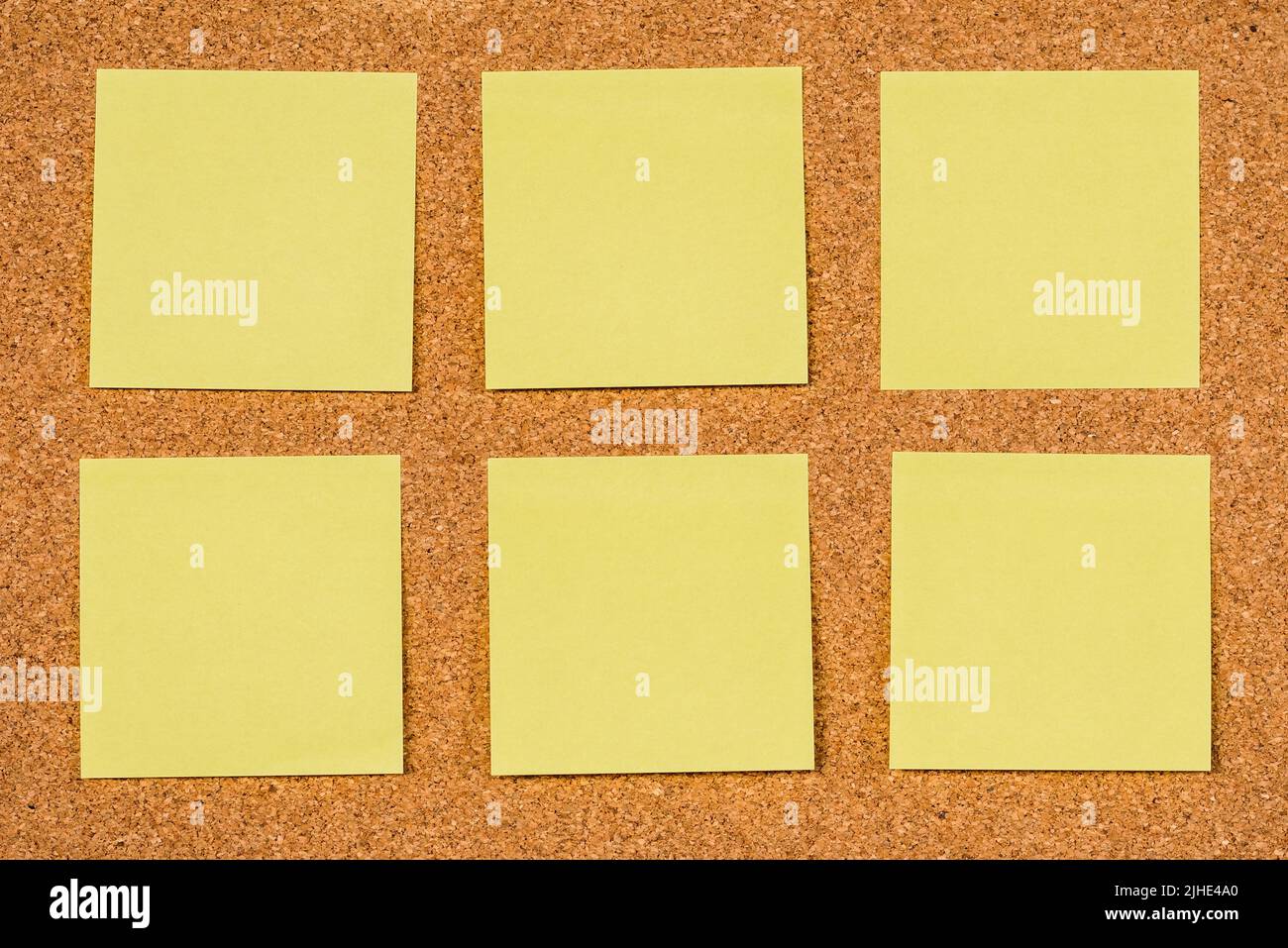 Six empty yellow sticky notes on a cork board, copy past Stock Photo