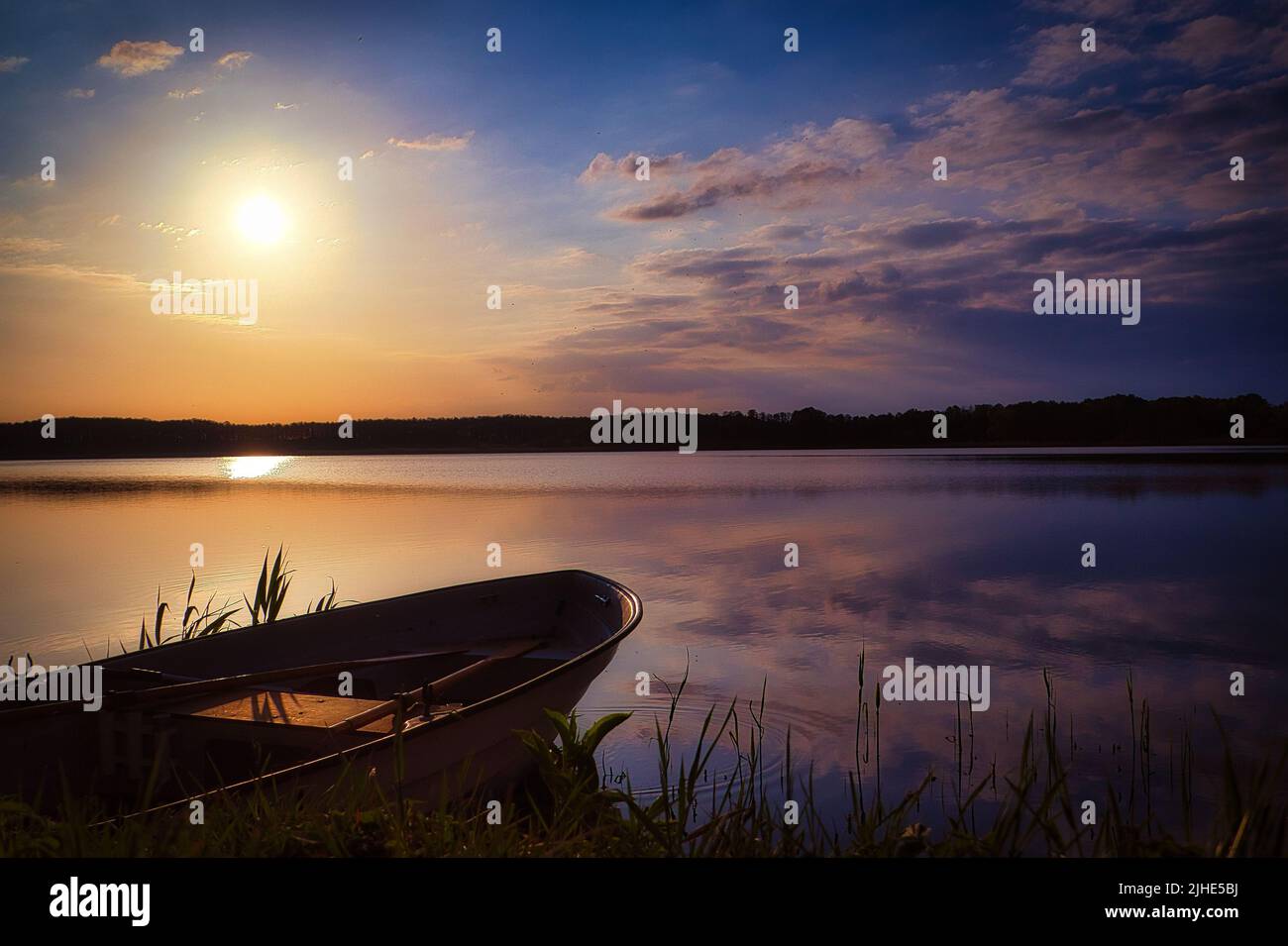 A sunset landscape of blue sky reflecting on the lake with a boat Stock ...