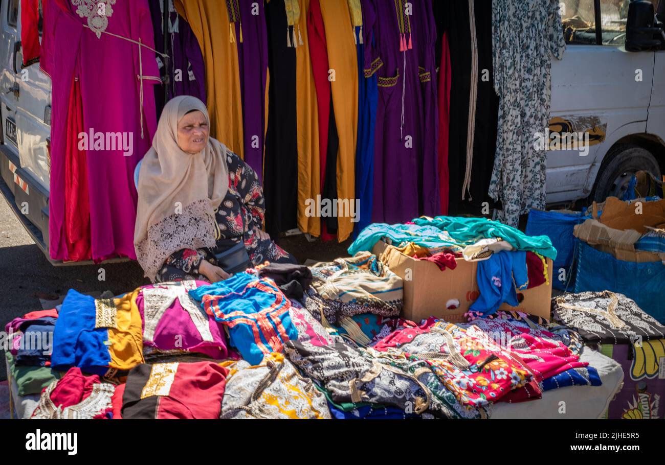 An elderly woman sells woman's clothing at the Sunday Souk, a aeekly market in Sousse, Tunisia. Stock Photo