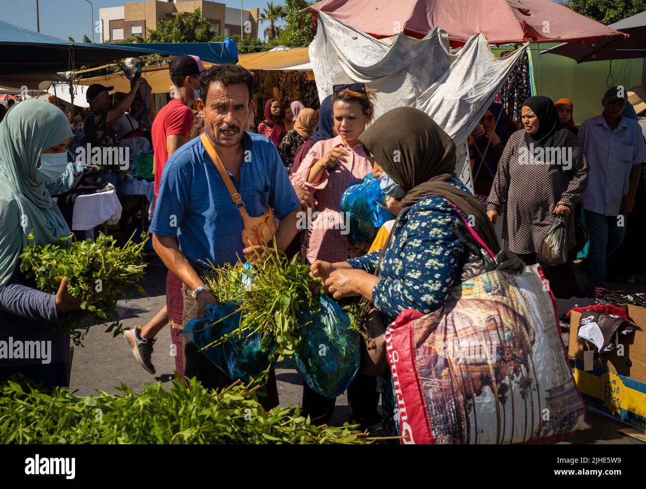 A women buys mint from a vendor at the Sunday Souk, a weekly market in Sousse, Tunisia. Stock Photo