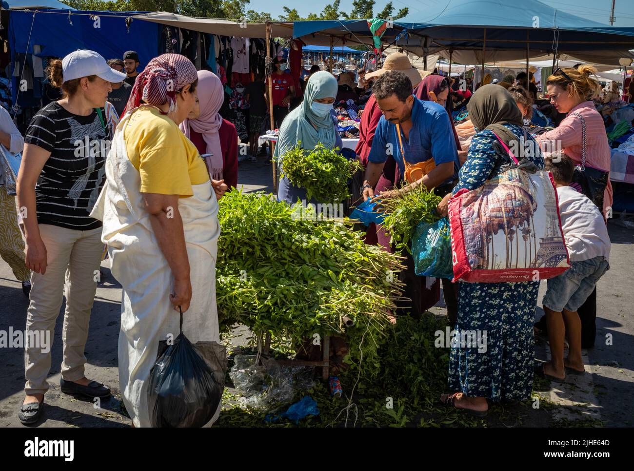 Women crowd round a mint seller at the Sunday Souk, a weekly market in Sousse, Tunisia. Stock Photo