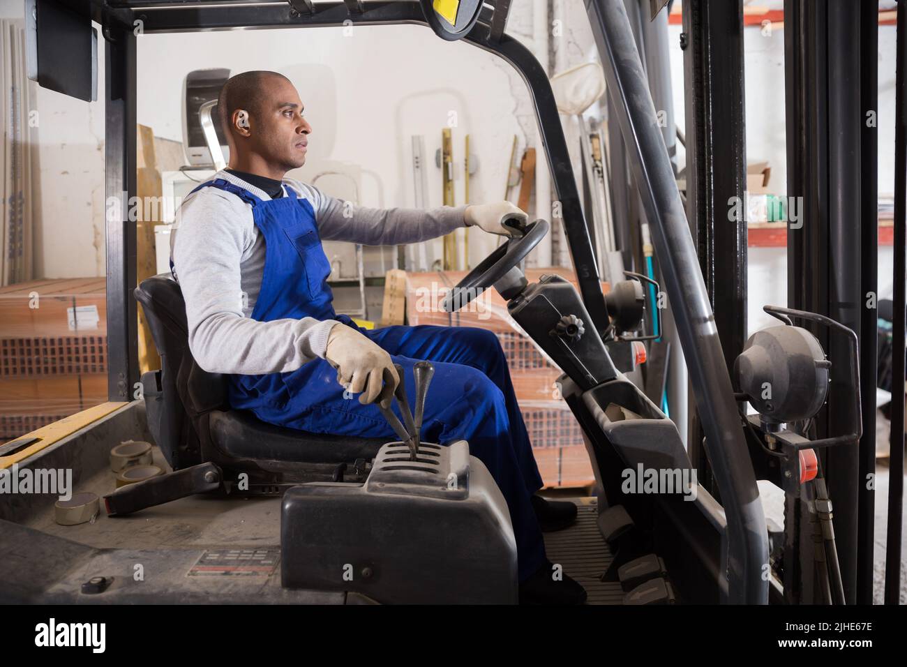 Latin American operator of forklift working in construction hypermarket