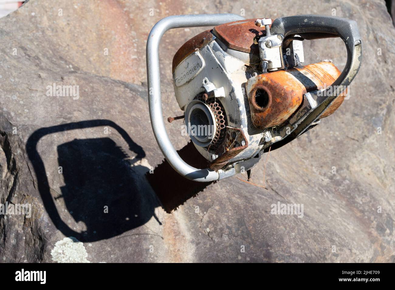 Old chainsaw embedded in a rock, Owhiro Bay, Wellington, North Island, New Zealand Stock Photo