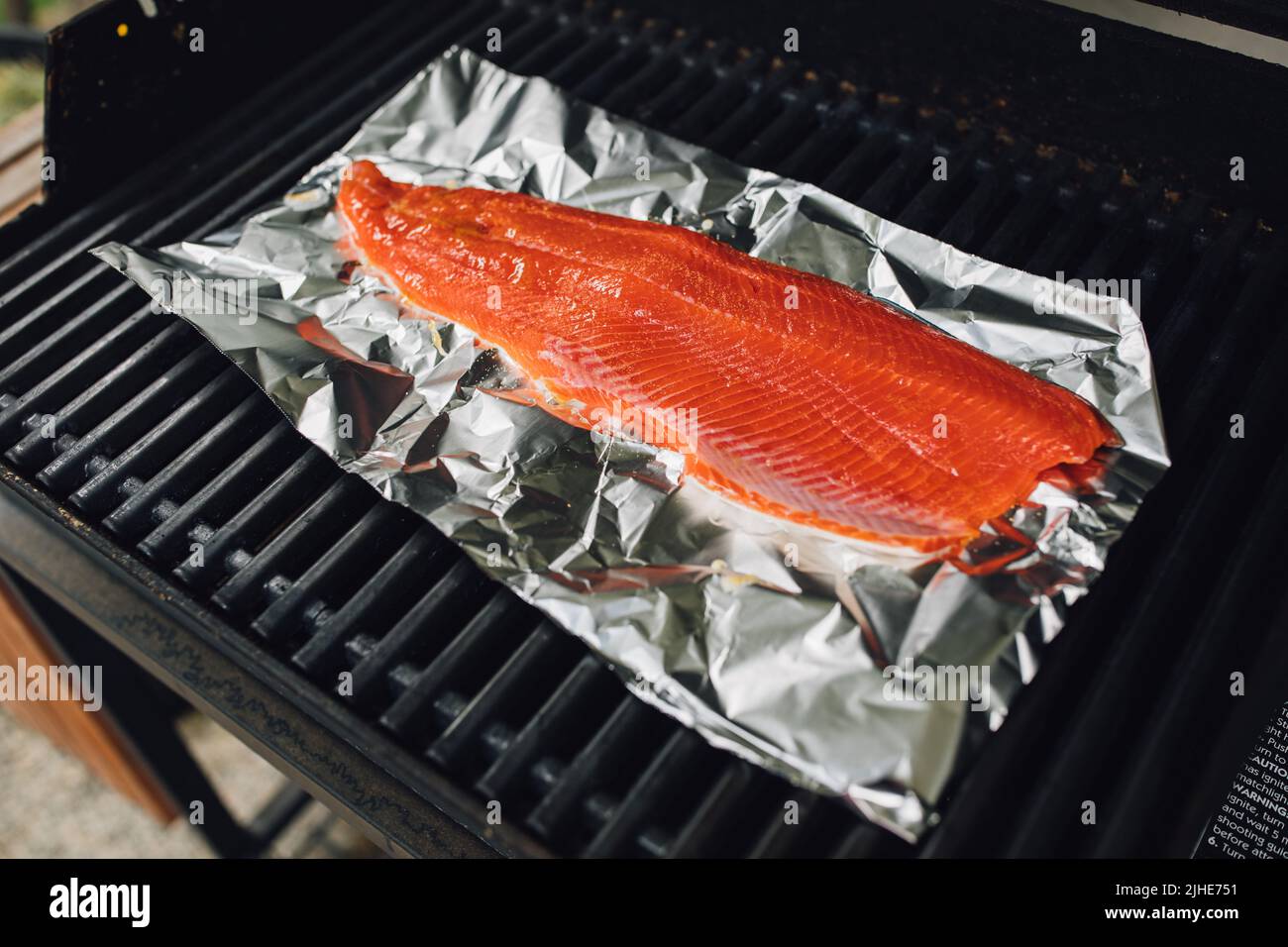 whole Copper River Salmon filet on foil on barbecue grill Stock Photo