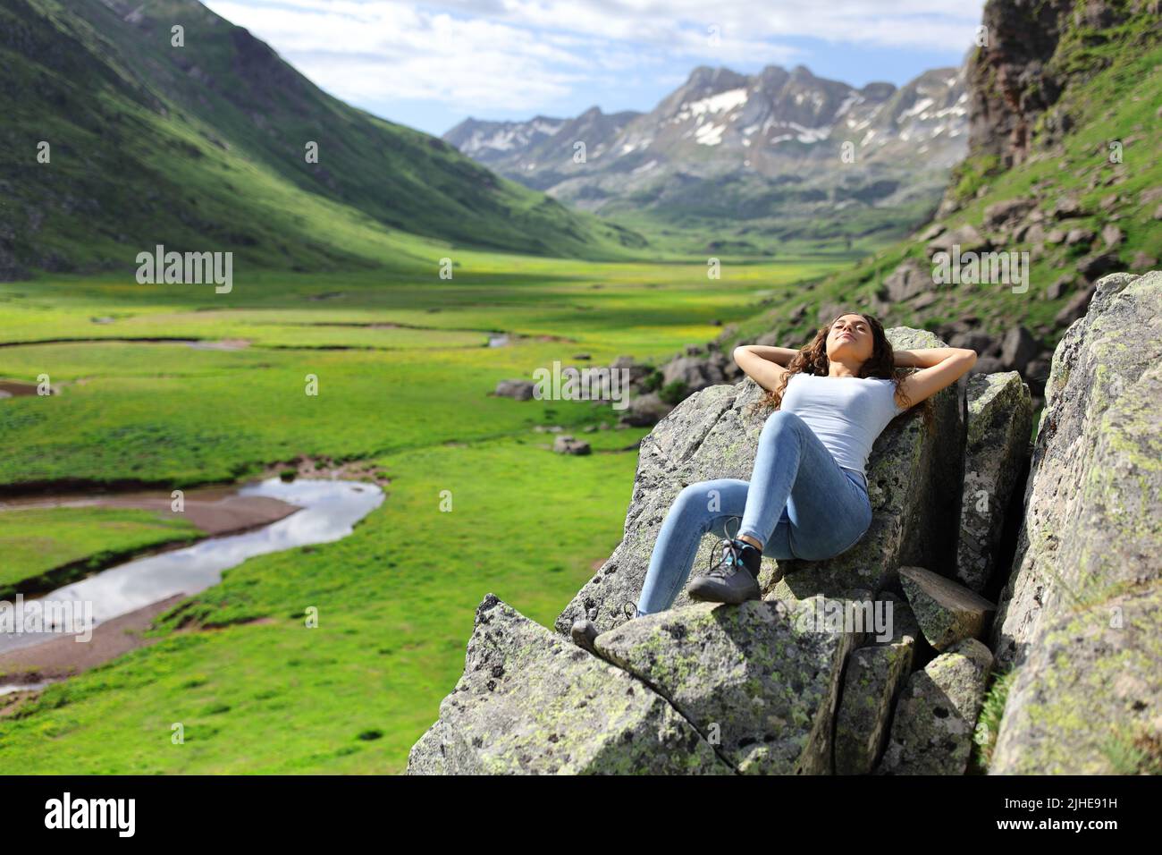 Full body portrait of a woman resting in a beautiful mountain landscape Stock Photo