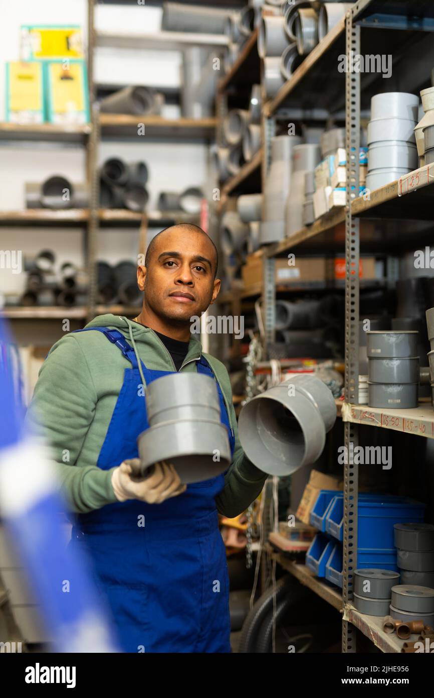 Pvc Salesman Salesman in overalls with plumbing fittings at hardware store warehouse ...