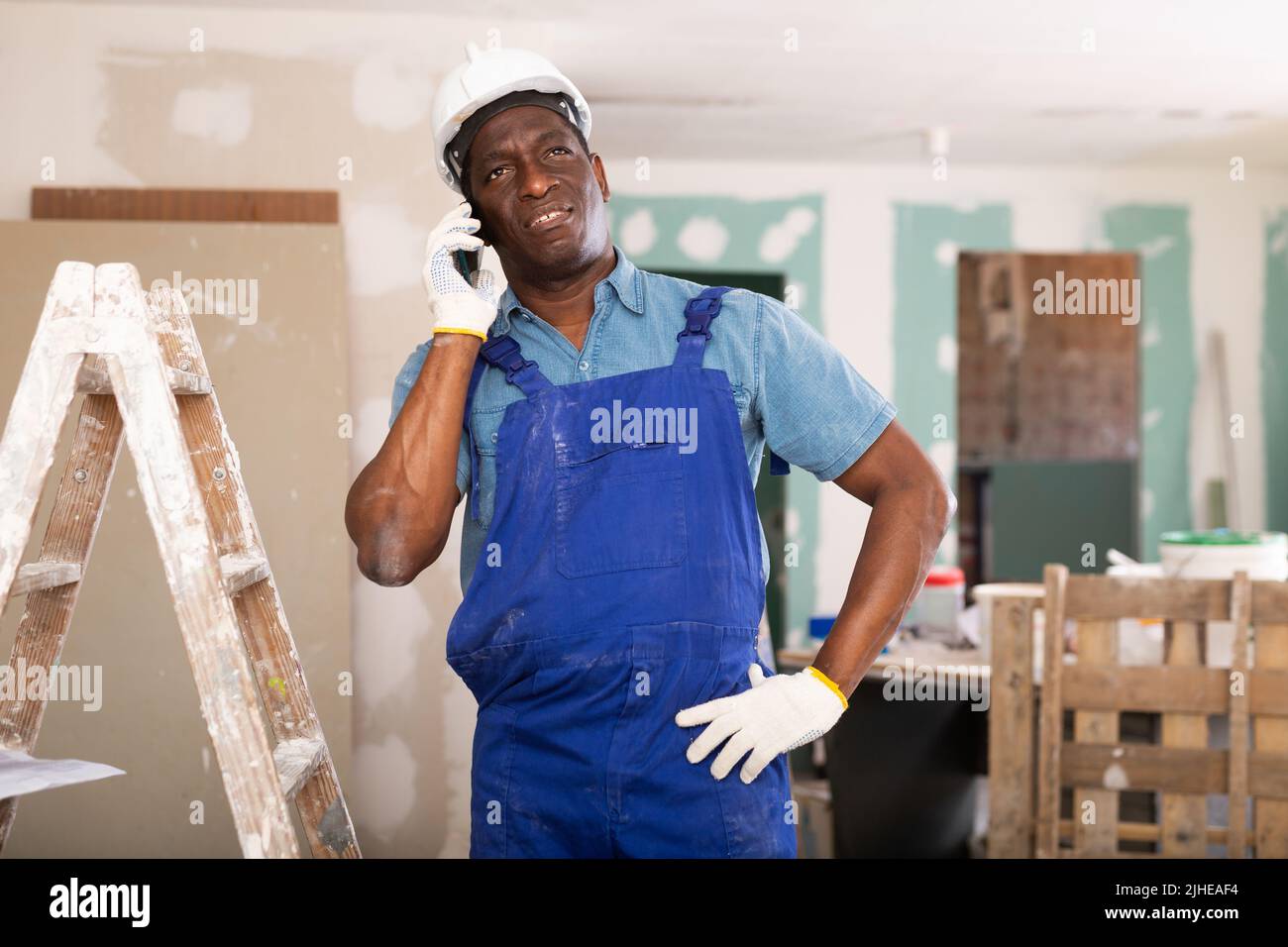 African american builder is talking on a mobile phone Stock Photo