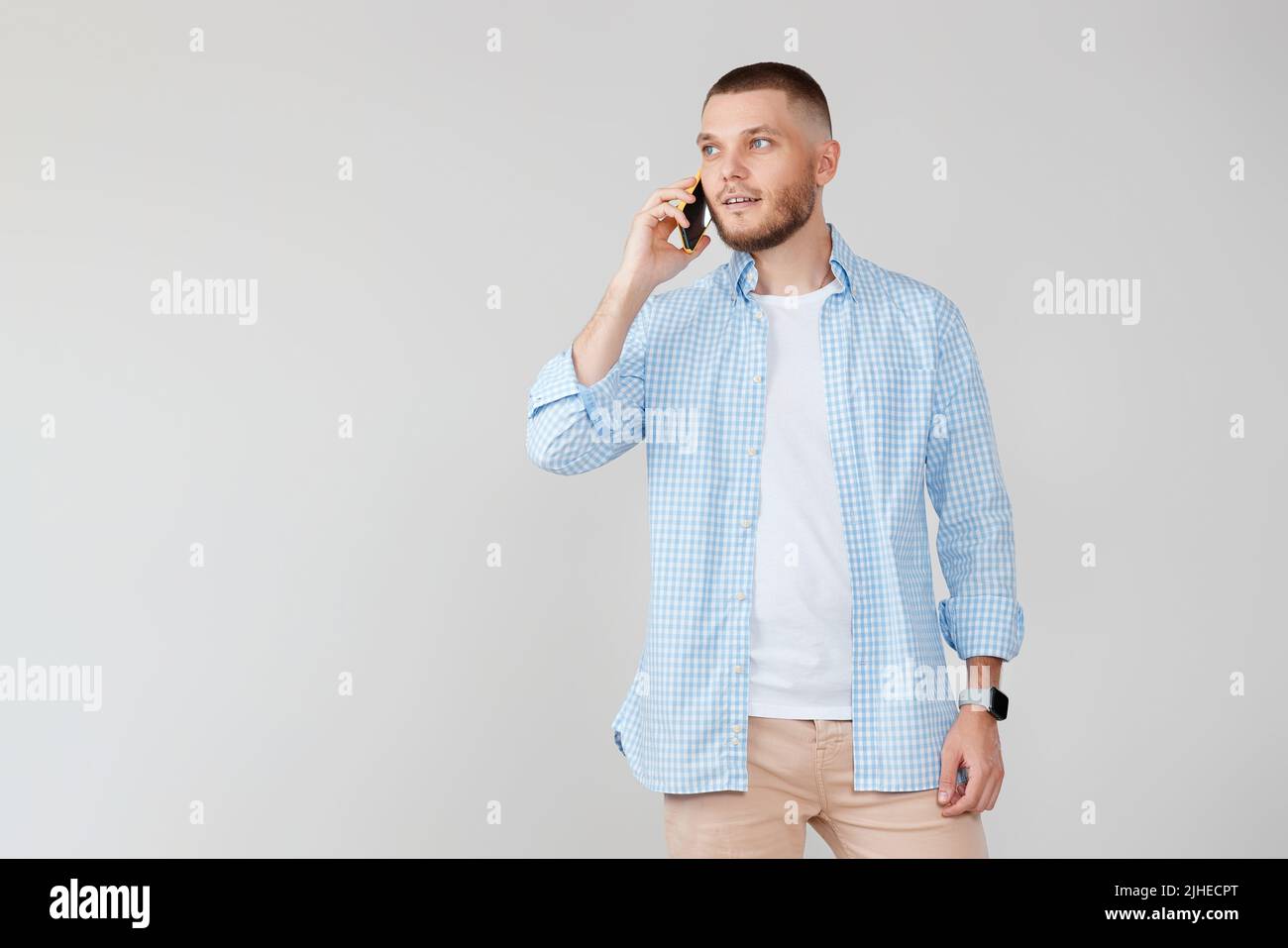 Handsome young man using cell phone while standing Stock Photo