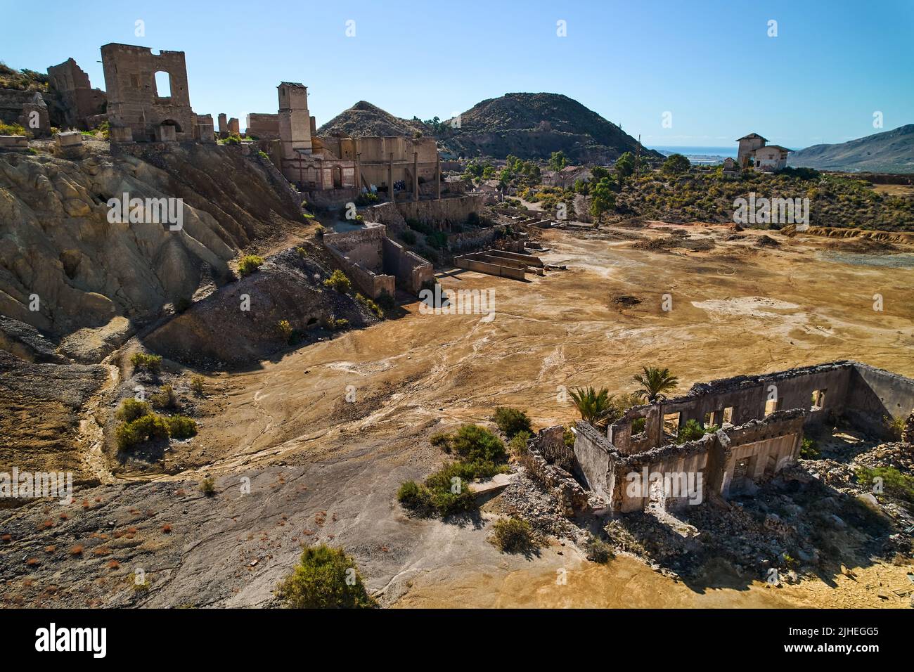 Panoramic aerial shot, drone point of view old abandoned buildings of mines of Mazarron in Murcia on blue sky background during sunny summer day. Mine Stock Photo