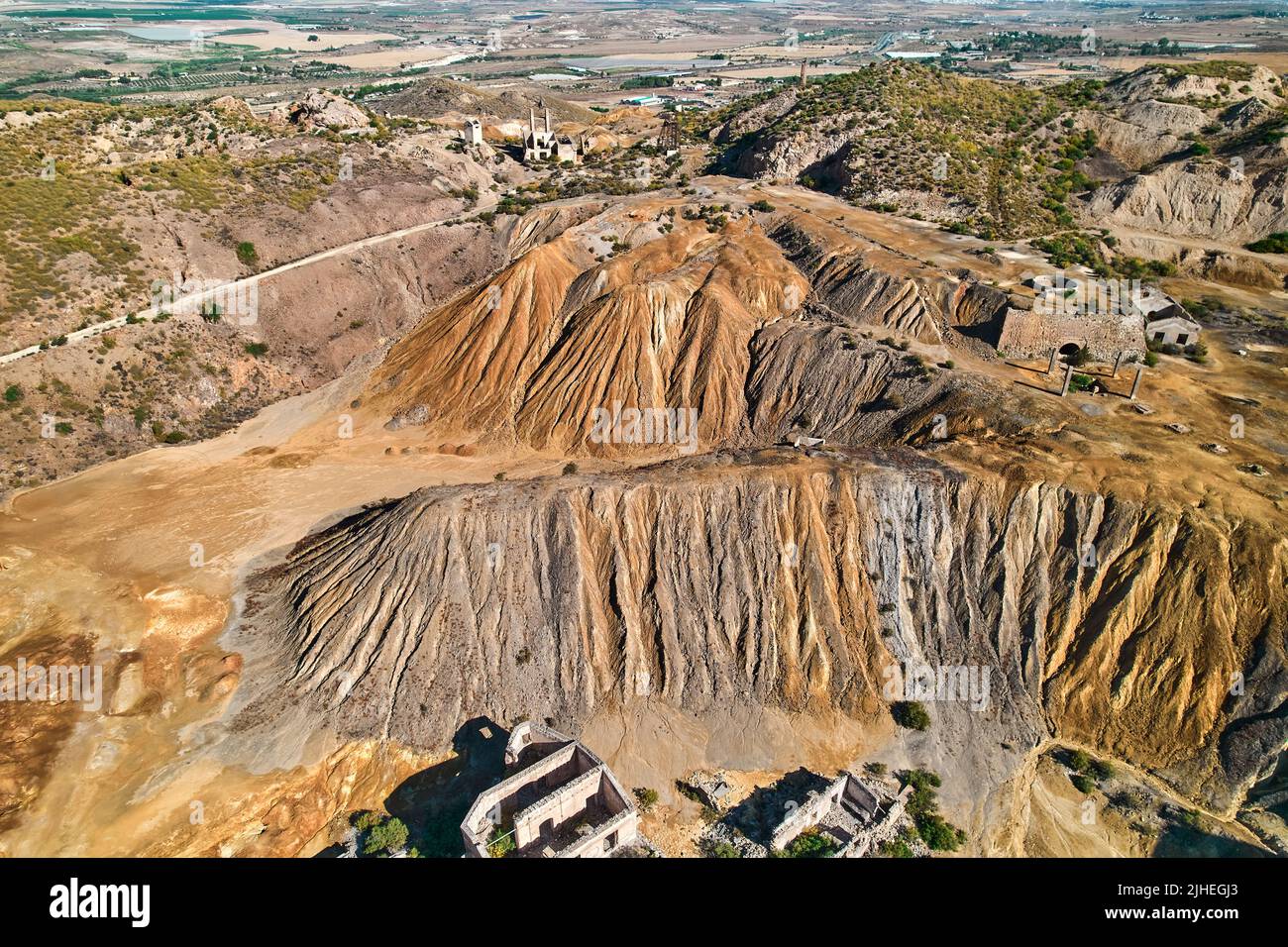 Panoramic aerial shot, drone point of view from above old abandoned mines of Mazarron in Murcia on blue sky background during sunny summer day. Minera Stock Photo