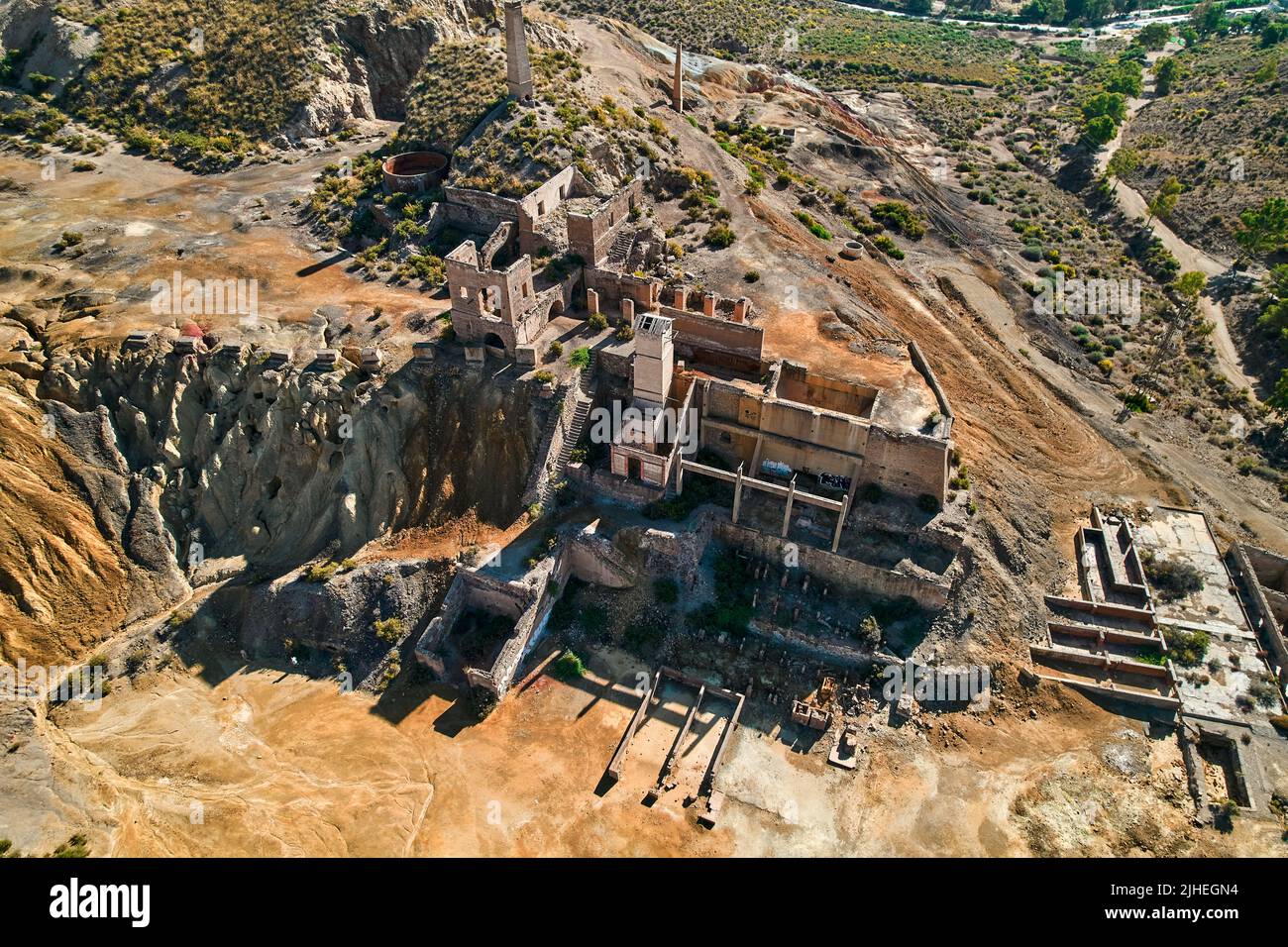 Aerial shot, drone point of view old abandoned buildings of mines of Mazarron in Murcia on blue sky background during sunny summer day. Mineral extrac Stock Photo