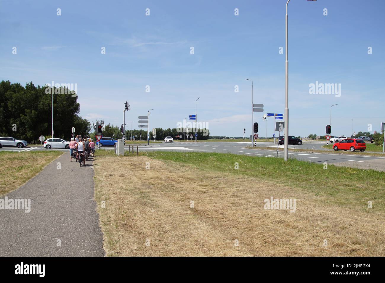 Crossroads from the Dutch city of Alkmaar to Bergen. Cars, cyclists, pasture. Dry grass in the verge. Sunny. summer, Netherlands Stock Photo