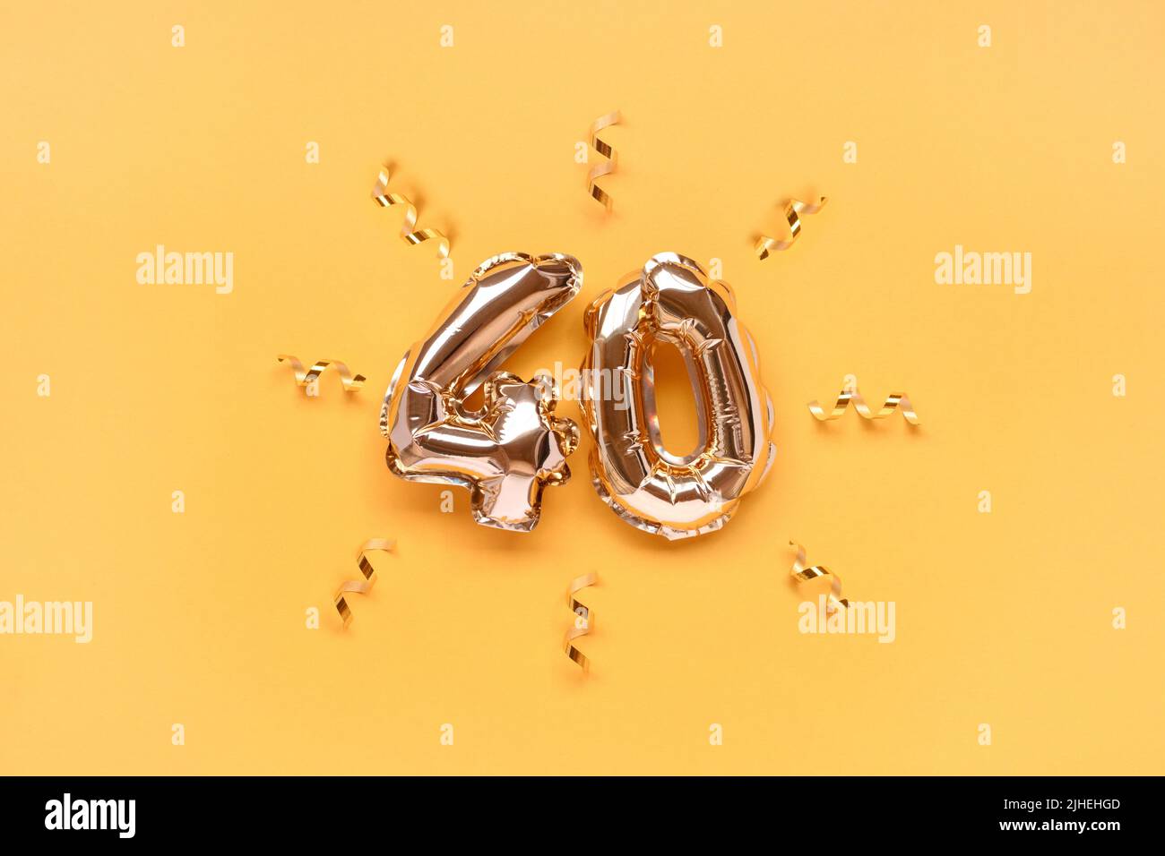 Number 40 air balloons with ribbon confetti on a gold colored background. Stock Photo