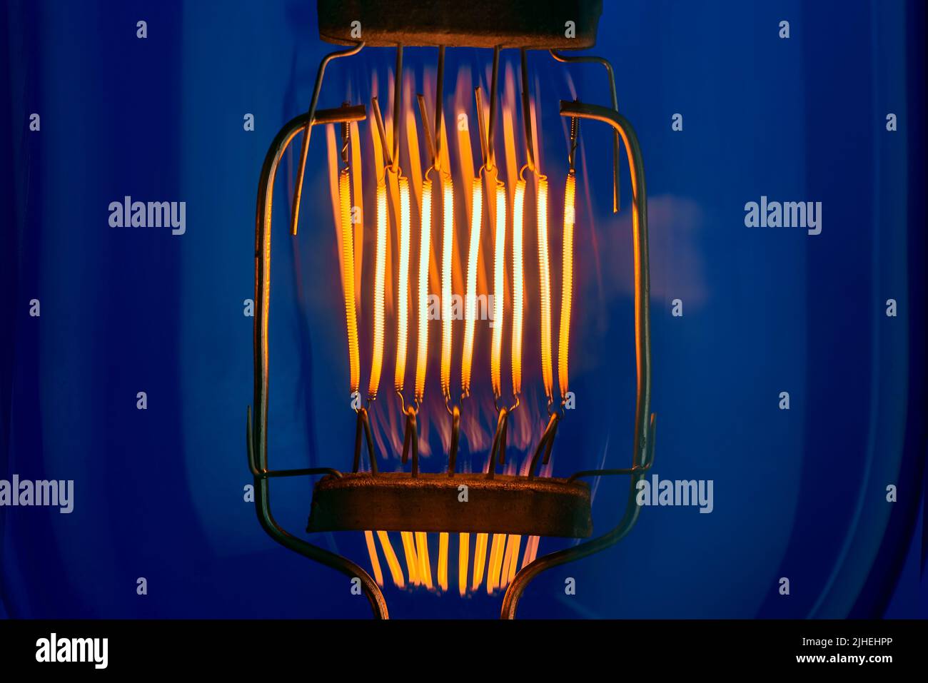 tungsten filament of high power incandescent lamp on blue background close up Stock Photo