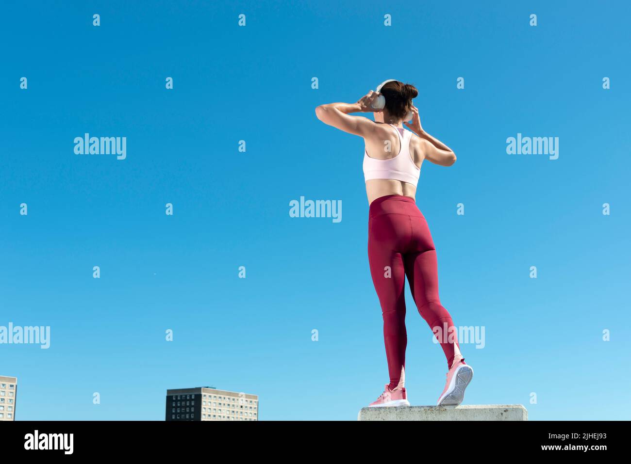 Rear view of a sporty woman holding heaphones on her head. rear view, urban background. Stock Photo