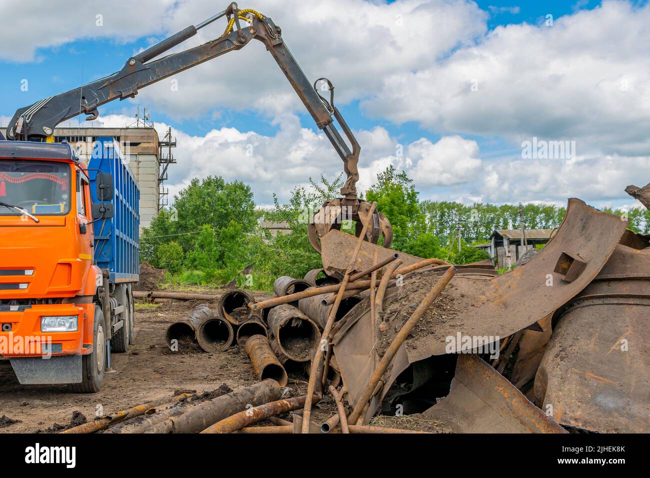 Scrap metal waste (steel and cast iron pipes) is loaded into truck